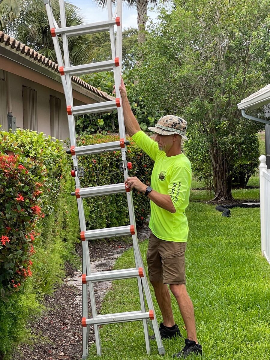 Iguana Gone technician setting up a ladder for rooftop iguana removal at a South Florida home